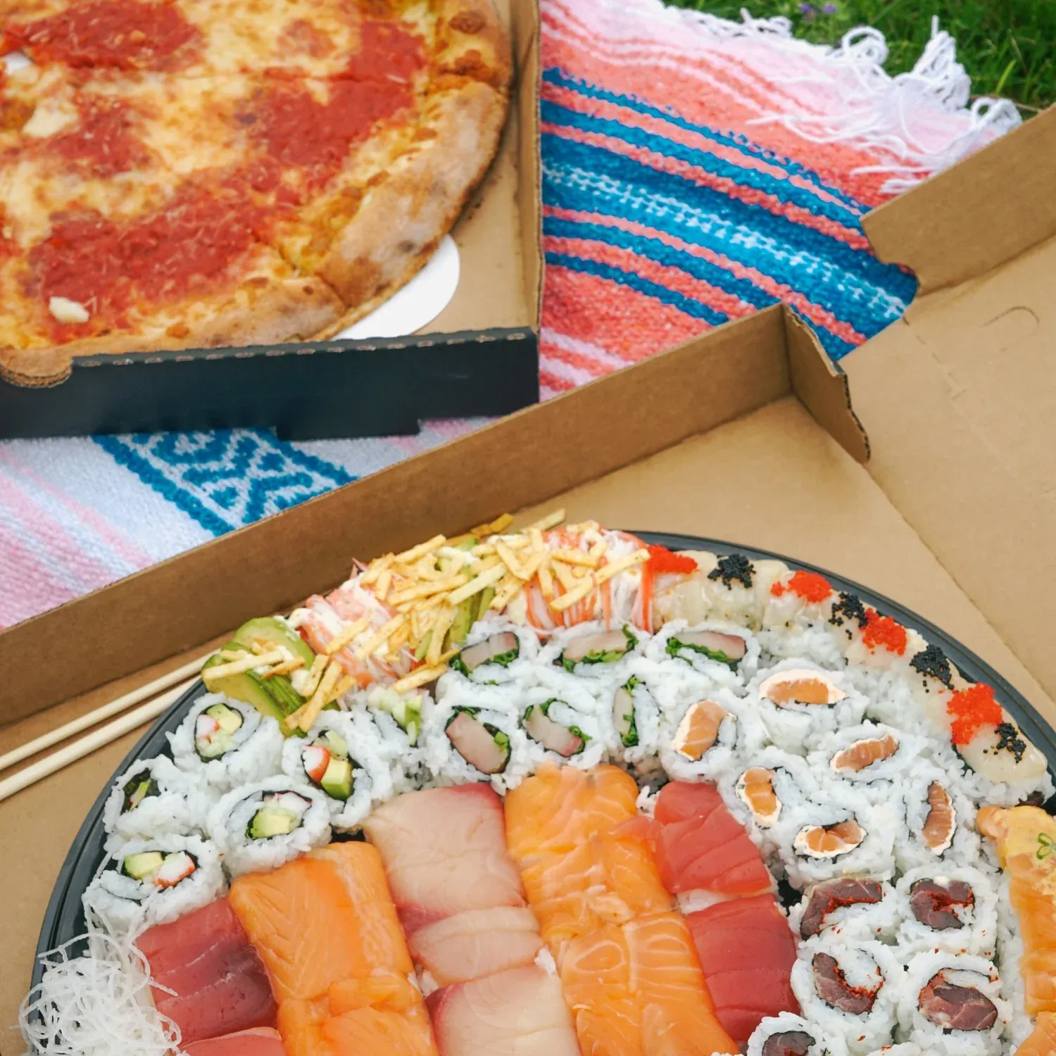 Box of sushi rolls and a pizza from Pizzeria Maki catering