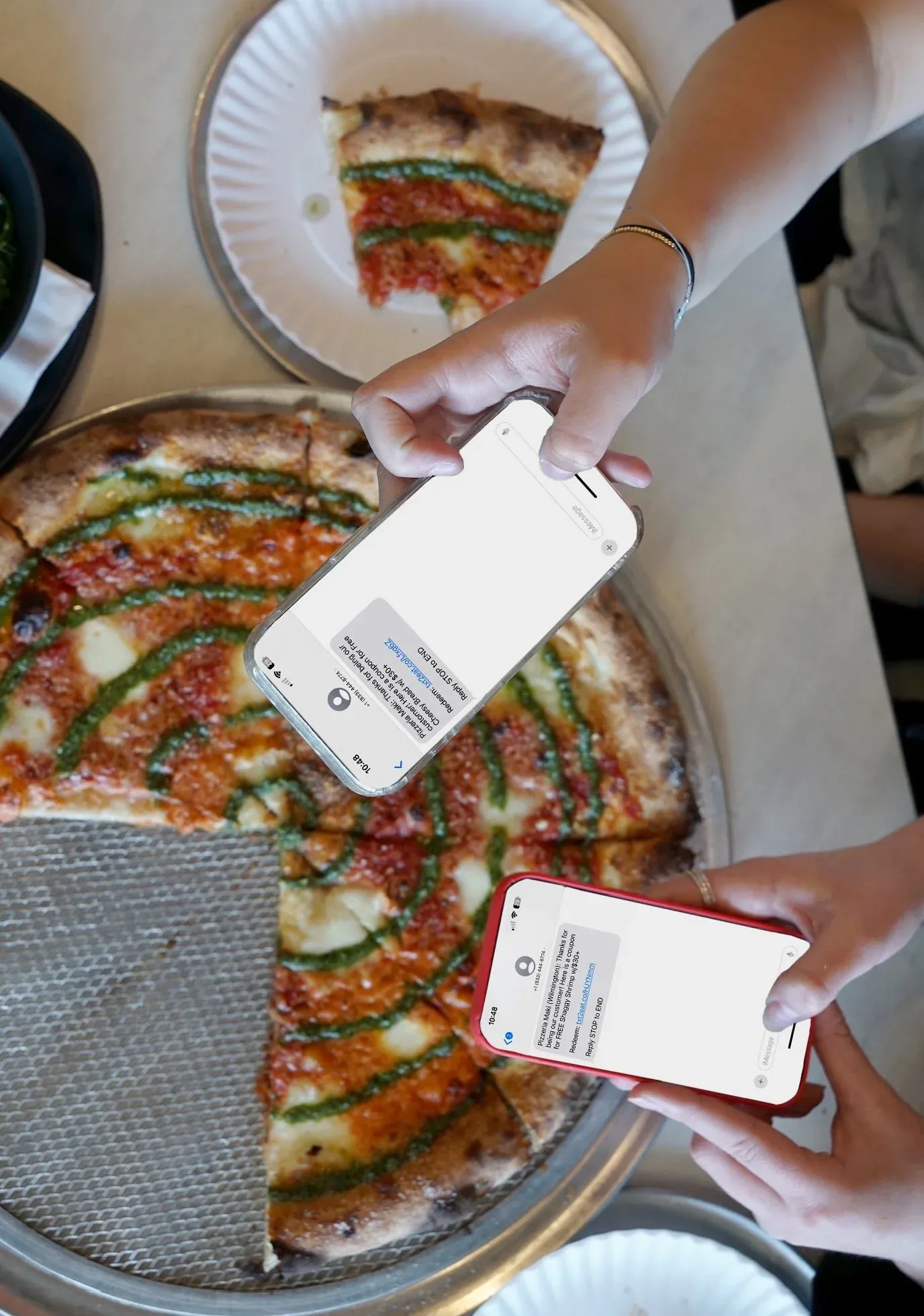 Pizzeria Maki rewards app on two phones over a pizza
