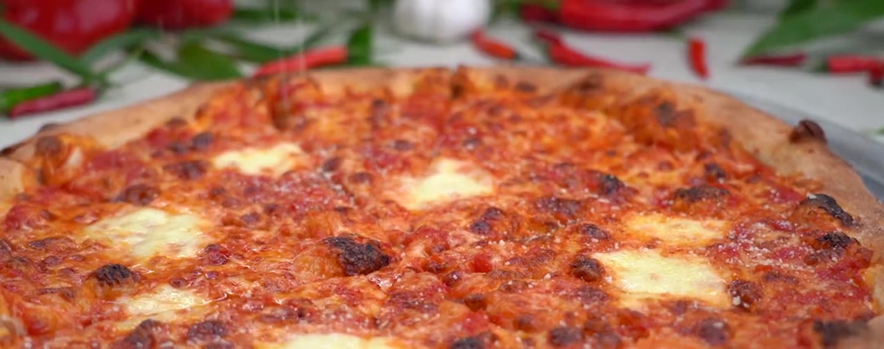 Grated cheese falling onto a fresh pizza